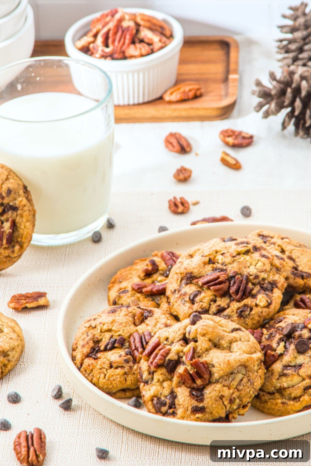 Brown Butter Pecan Chocolate Chip Cookies (Gluten-Free) A plate of golden-brown cookies with a glass of milk, invitingly presented.