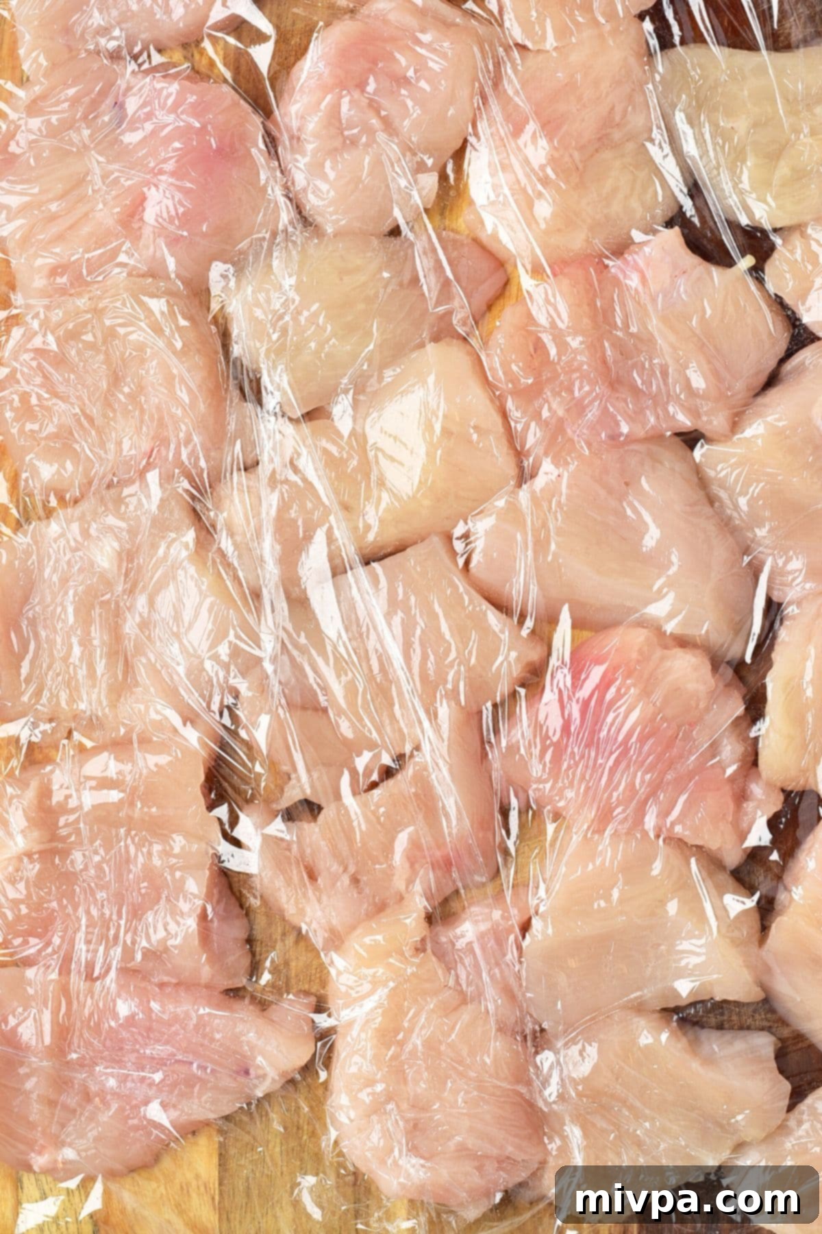 Gluten-Free Turkey Nuggets Turkey pieces covered in plastic wrap on a cutting board.