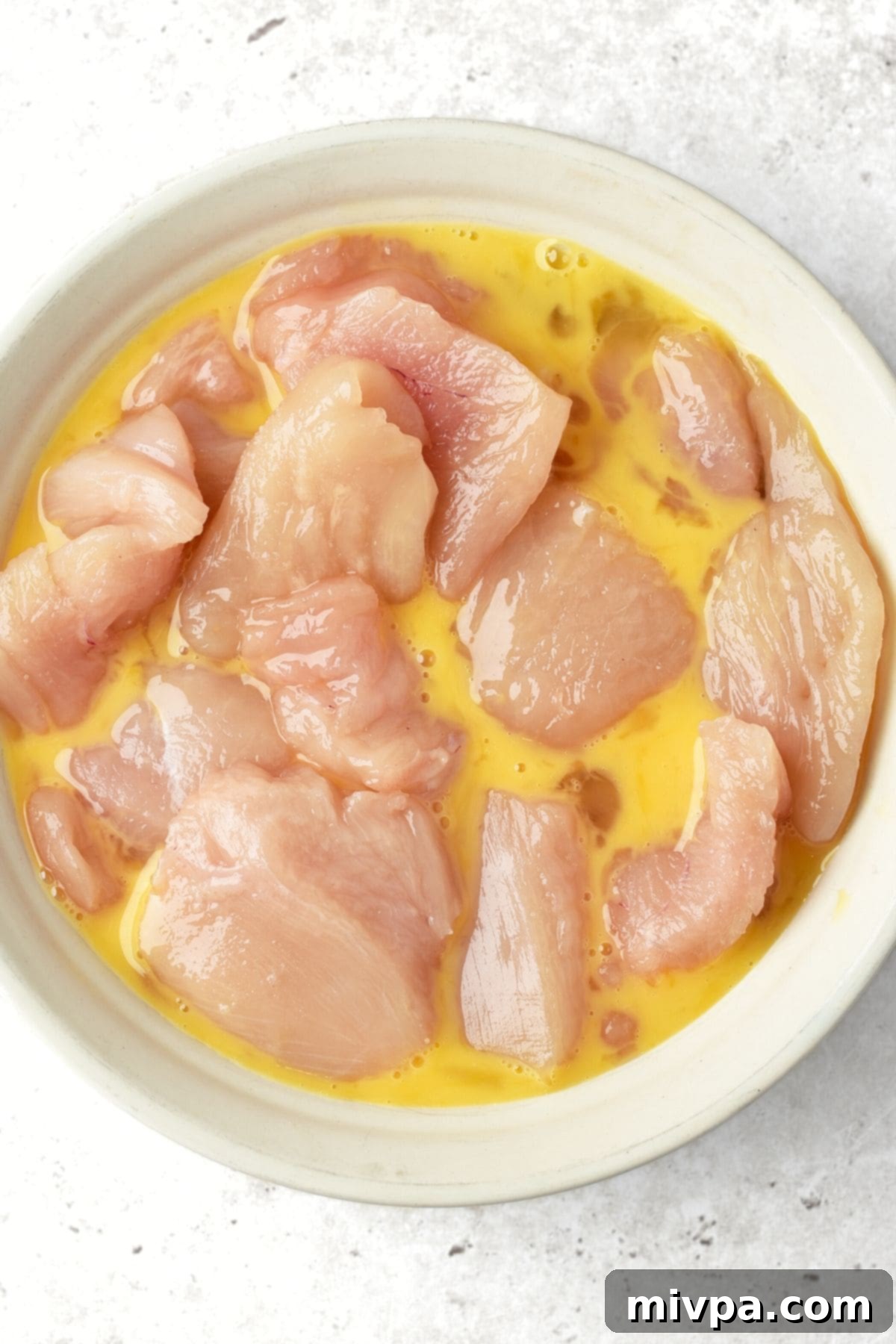 Wholesome Turkey Bites Gluten Dairy Free 2 Turkey pieces being dipped in a bowl of beaten egg.