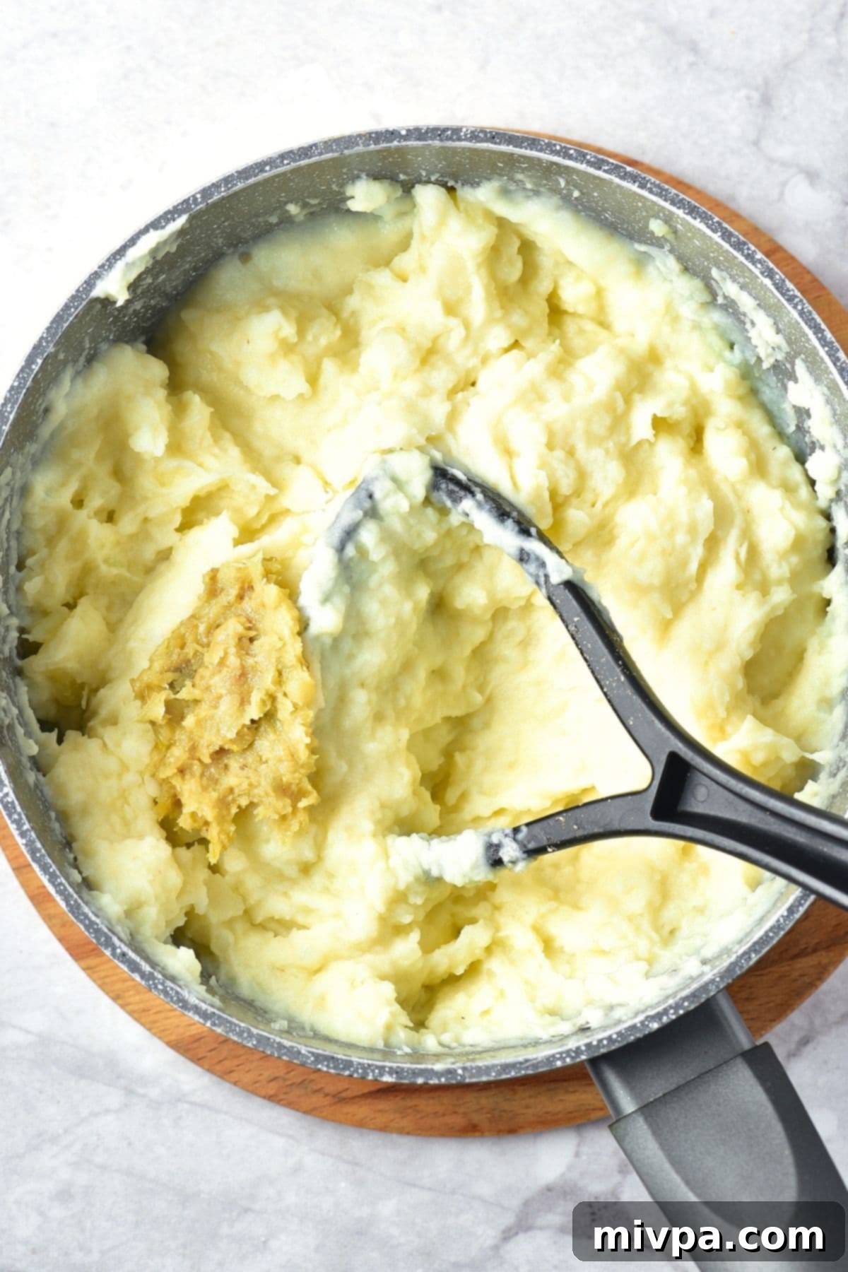 Gluten-Free Vegan Mashed Potatoes Mixing mashed garlic into mashed potatoes