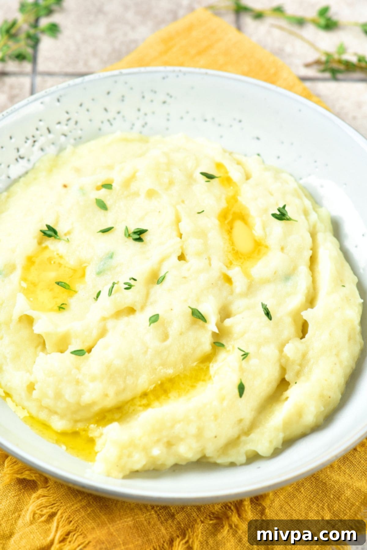 Creamy Potato Mash topped with Thyme Fresh thyme leaves on top pf creamy mashed potatoes