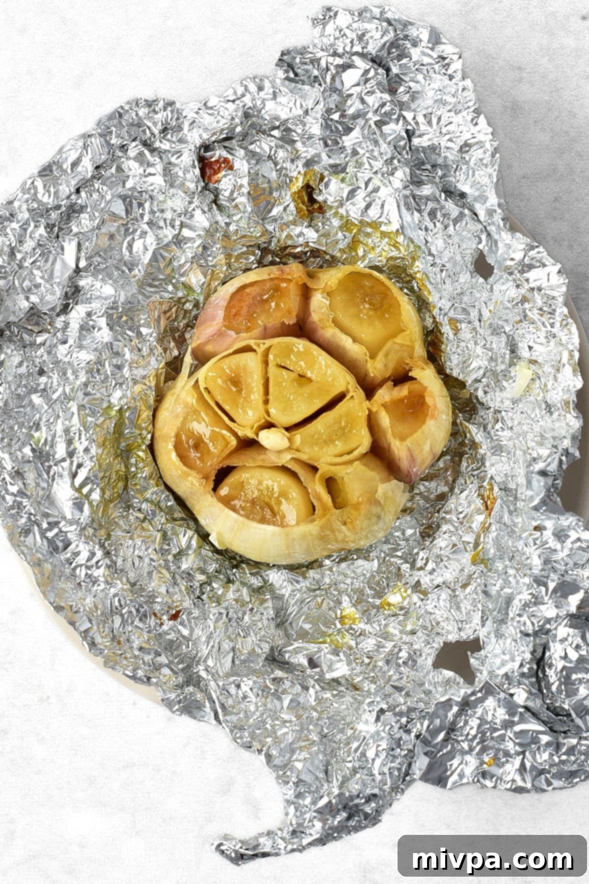 How to Make Garlic Mashed Potatoes A head of roasted garlic in aluminum foil.