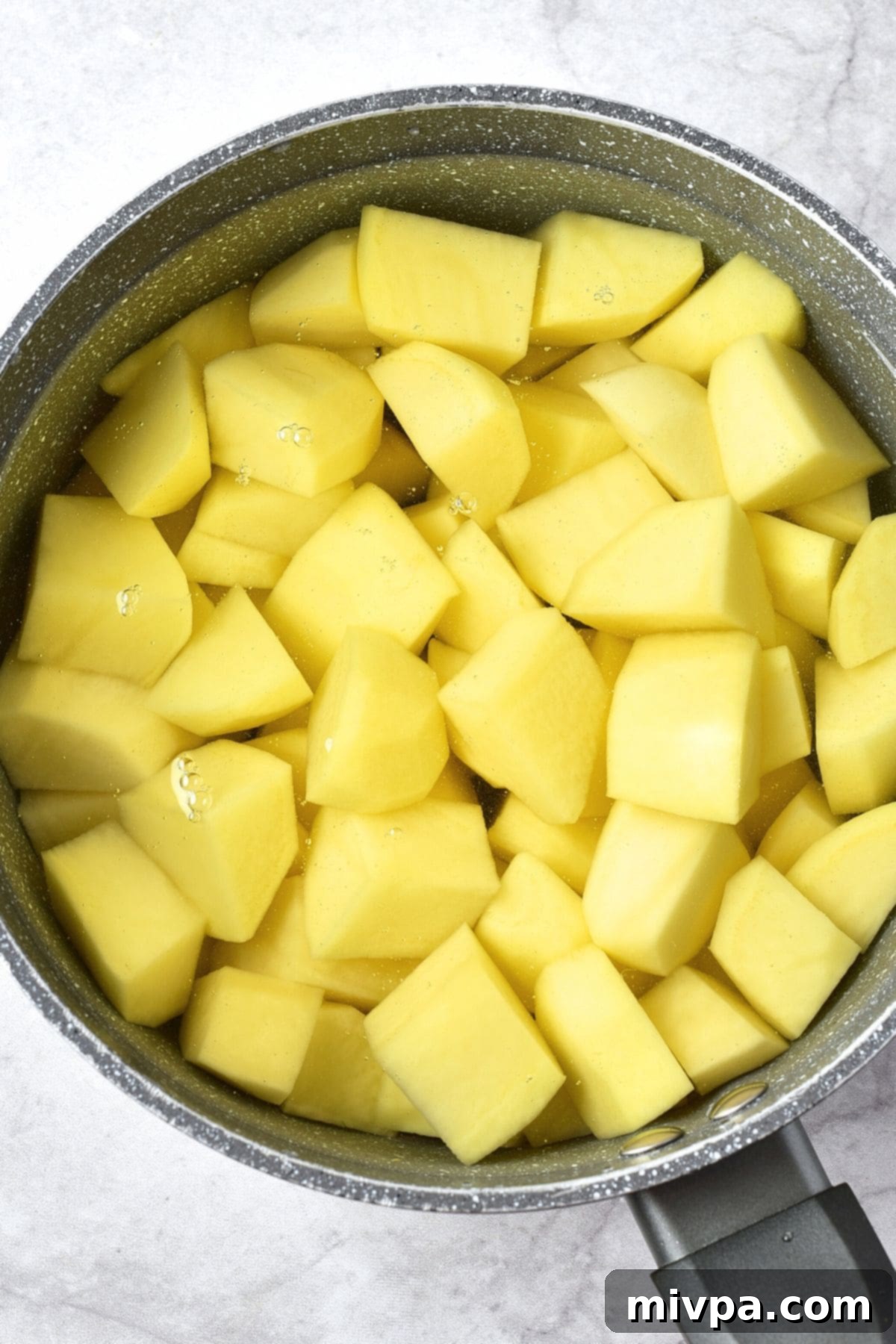 Creamy Garlic Mashed Potatoes (Gluten-Free, Vegan) Cubed potatoes in a pot of water