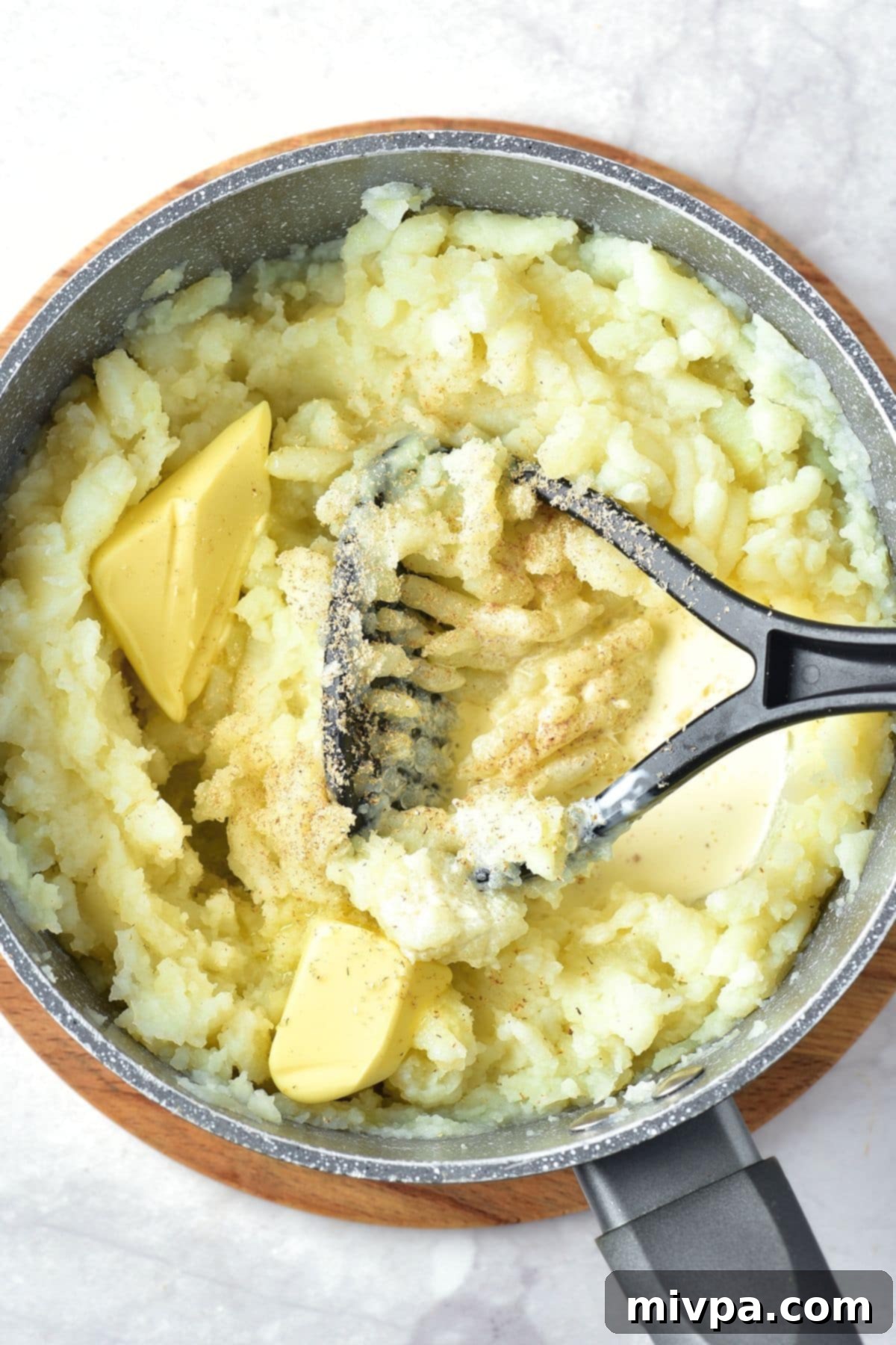 Gluten-Free Vegan Mashed Potatoes Mixing butter and spices into mashed potatoes