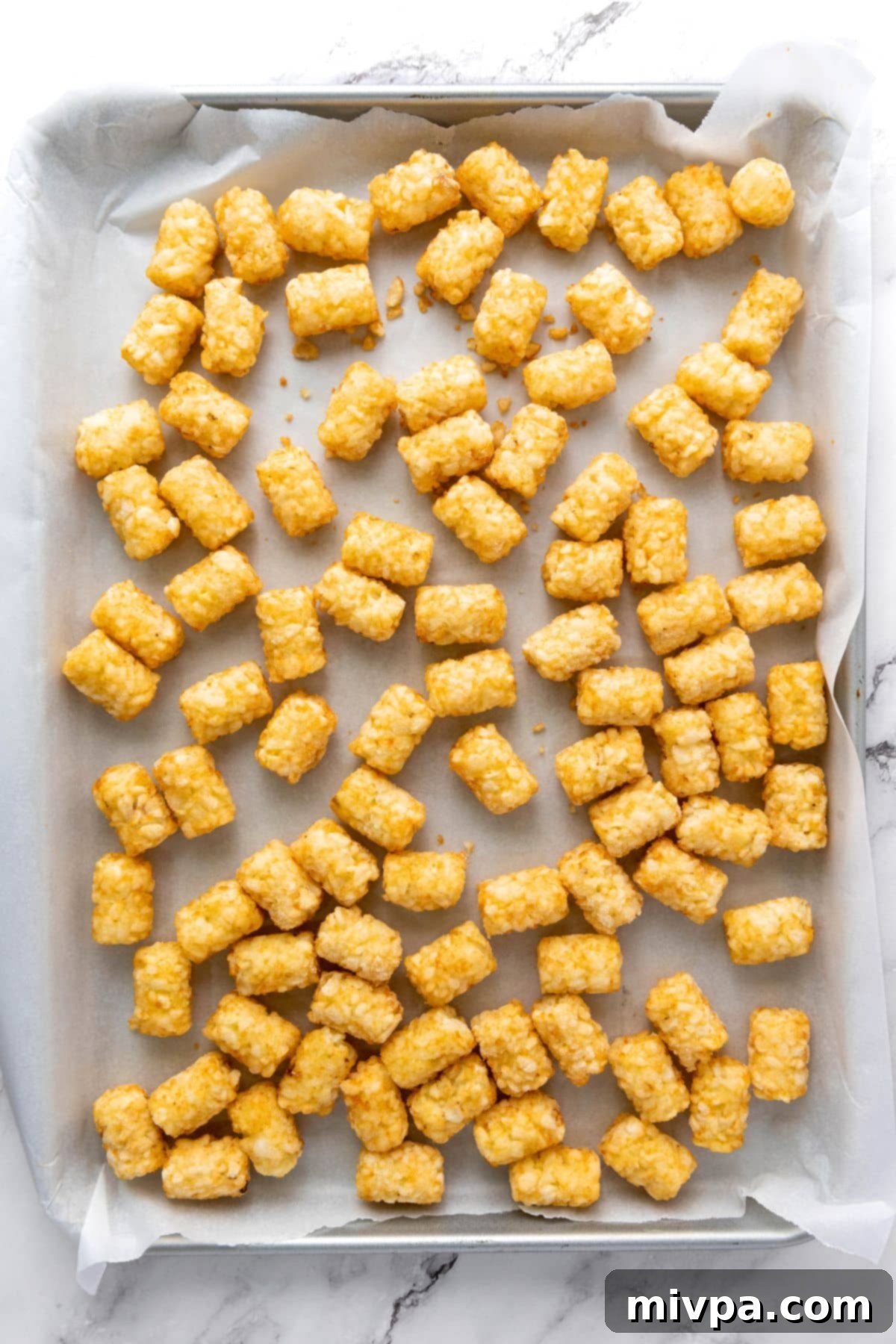 Cheesy Loaded Tater Tots (Gluten-Free) Frozen tater tots on parchment-lined baking sheet